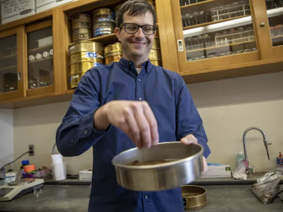 Joey Blankinship pinches some soil in his lab