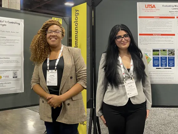 Two students stand next to posters at scientific conference