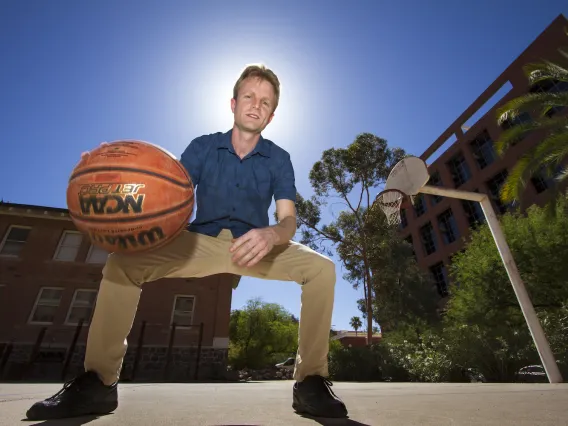 UA physicist Sam Gralla dribbles a ball on the basketball court.