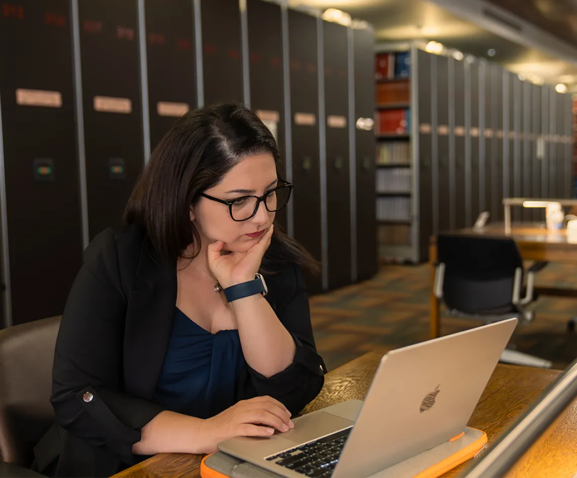 a woman sits types on a laptop