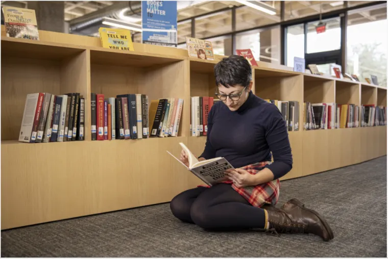 Megan Senseney reads a book on the floor of the library