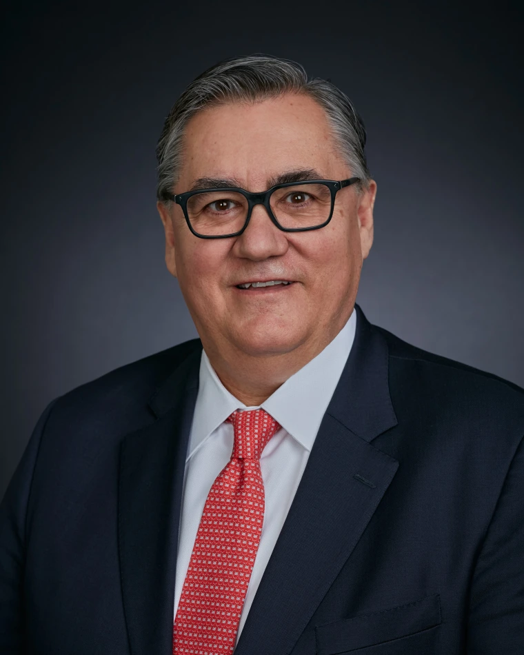 Photo of Tomás Díaz de la Rubia smiling, wearing a dark suit jacket and light red tie